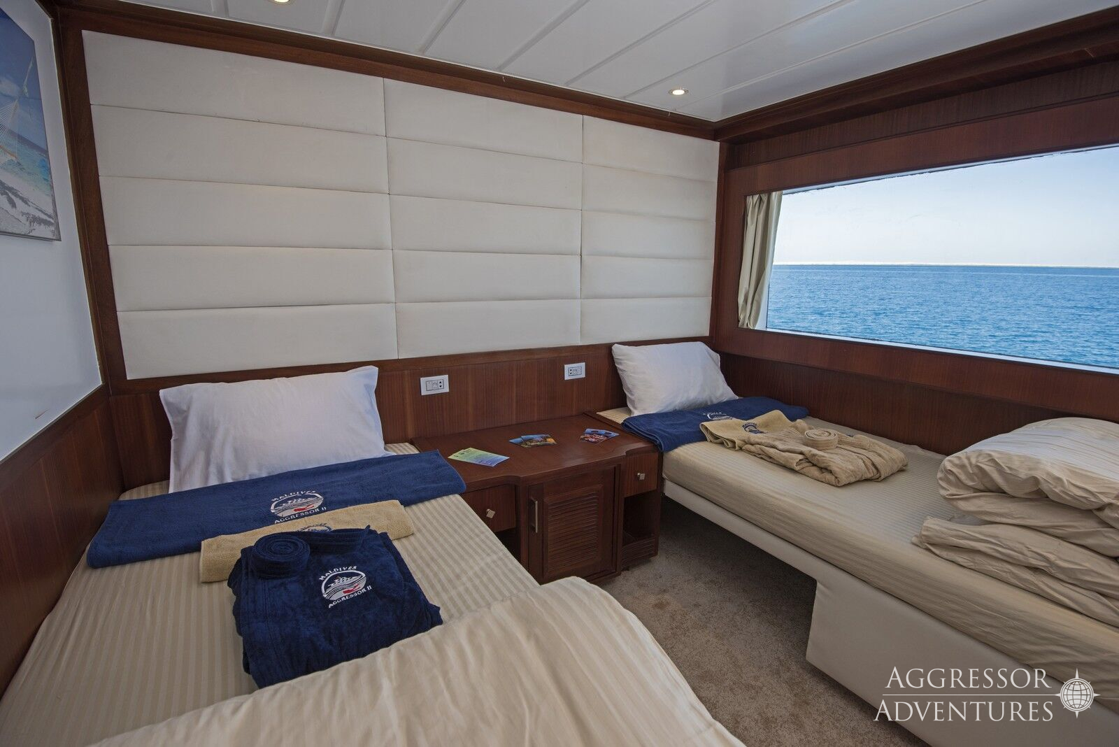 Comfortable twin stateroom with two single beds and porthole windows on Maldives Aggressor II