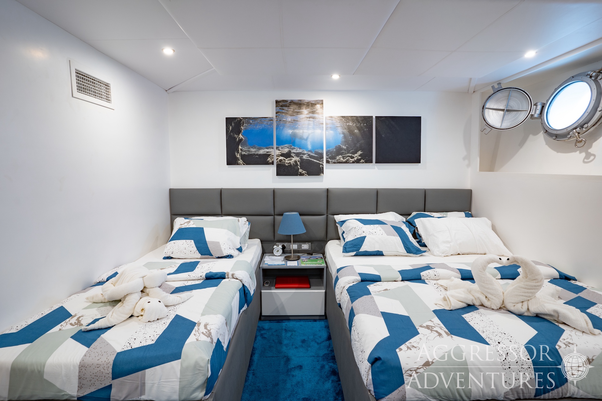 lower deck twin stateroom with double bed, single  and circular window on Philippines Aggressor