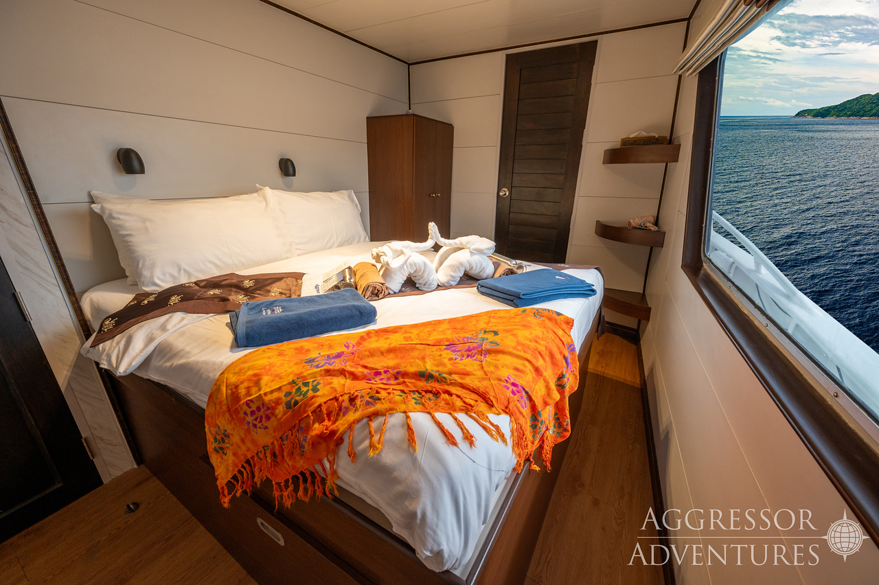 Luxury master suite stateroom with queen bed and panoramic windows aboard Thailand Aggressor