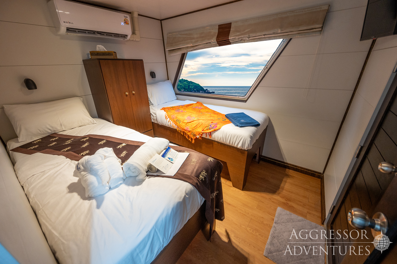 Comfortable twin stateroom with two single beds and porthole windows on Thailand Aggressor